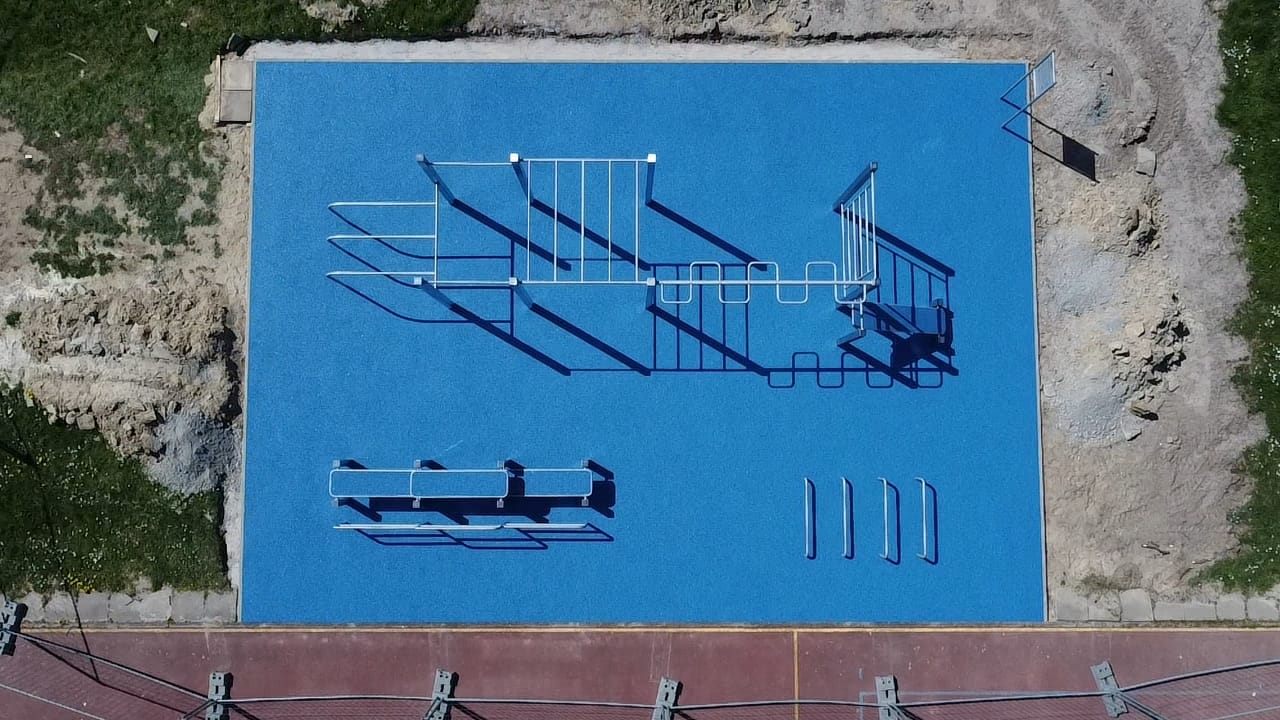 Rechteckige blaue Calisthenics-Fläche mit silbernen Geräten von oben.