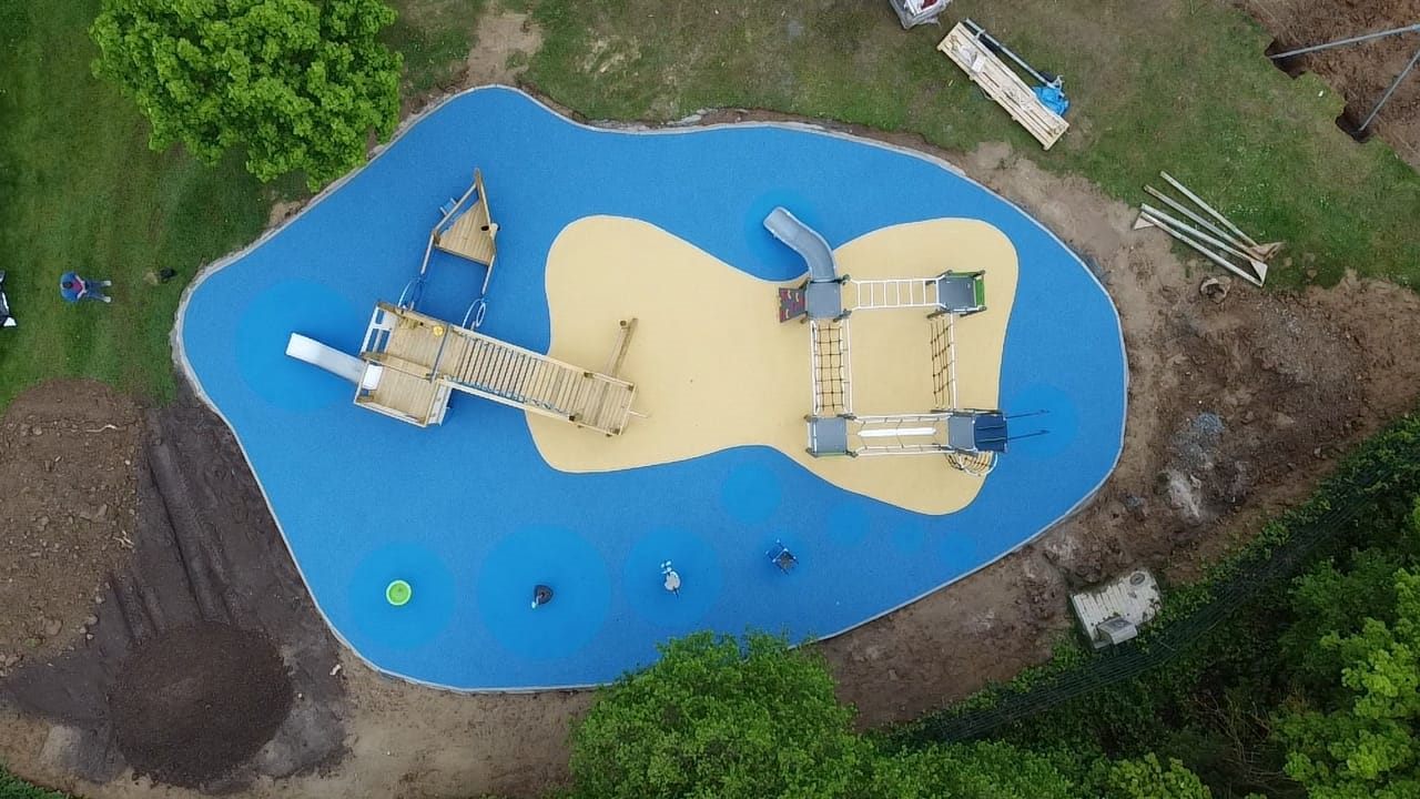 Organisch geformte blaue und sandfarbene Spielfläche mit Spielschiff von oben.