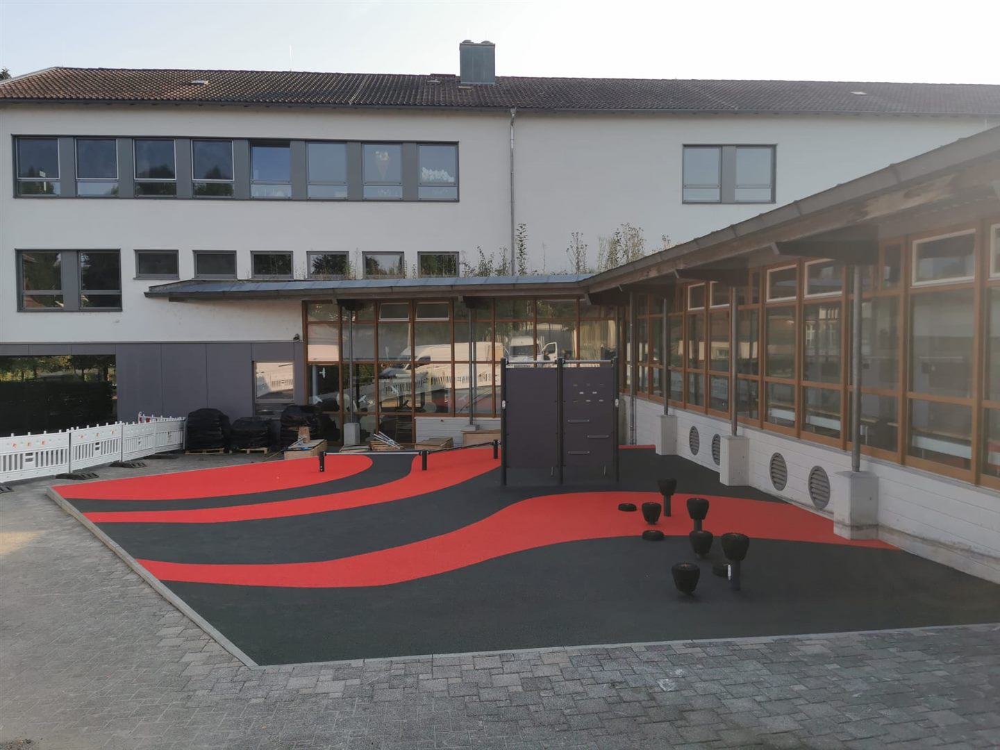 Rot-schwarze Bewegungsfläche im Hof eines Schulgebäudes.